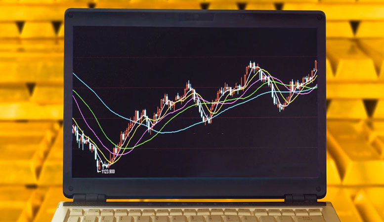 gold chart present in a laptop with gold bars behind it