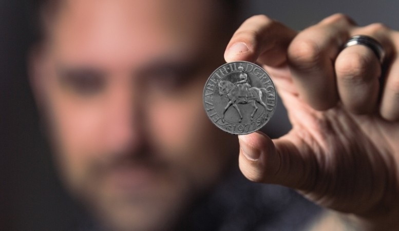 man holding a silver jubilee coin