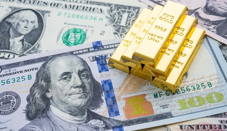 gold bars on top of us dollar bills