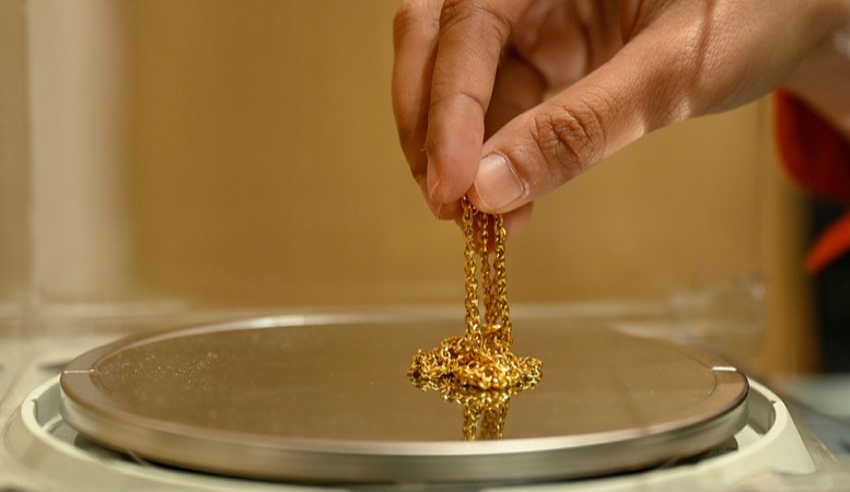 man weighing a gold jewelry in troy ounce