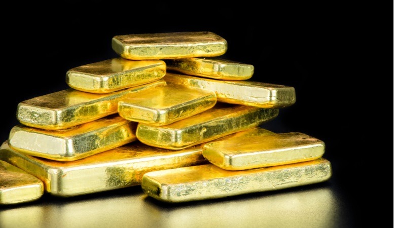 gold bars stacked in a pitch black background