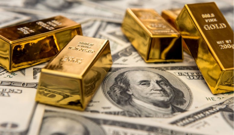 gold bars bullions lying on 100 dollar bills featured image