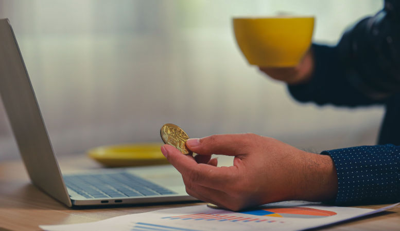 businessman planning to buy another gold coin in his laptop