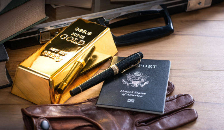 gold bars pen gloves and passport on wooden table featured image