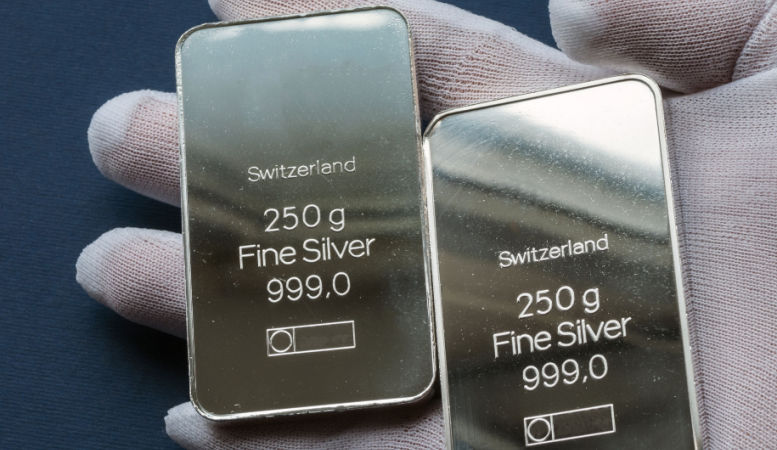 hand with protective glove holding two 250g minted silver bars