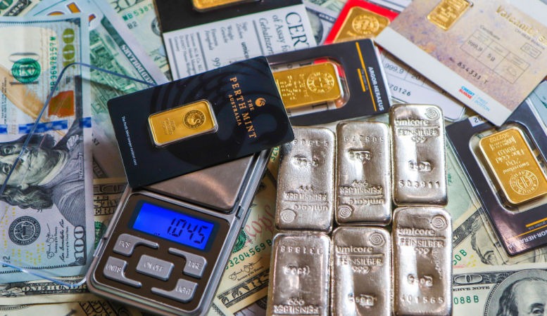 gold bars in weighing scale and silver bars on top of dollar bills featured image