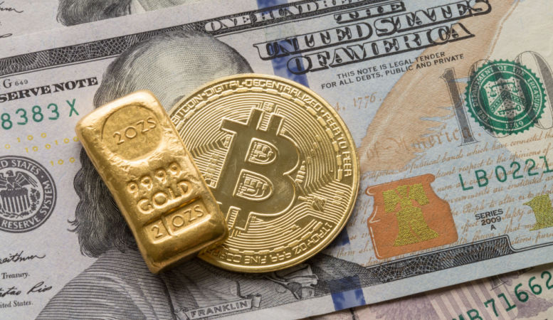 gold bullion and bitcoin cryptocurrency on one hundred dollar