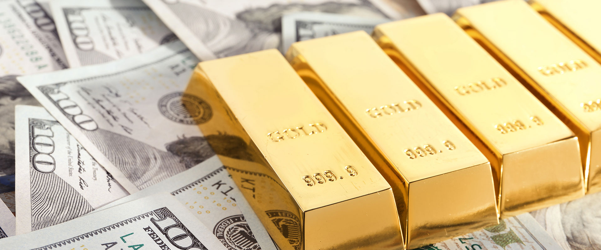 gold bars on pile of dollar bills