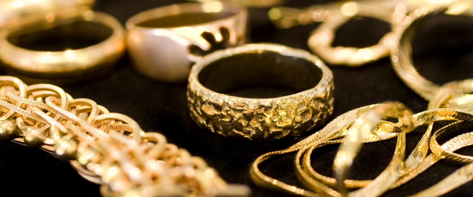 different kinds of gold jewelries sitting on a black cloth