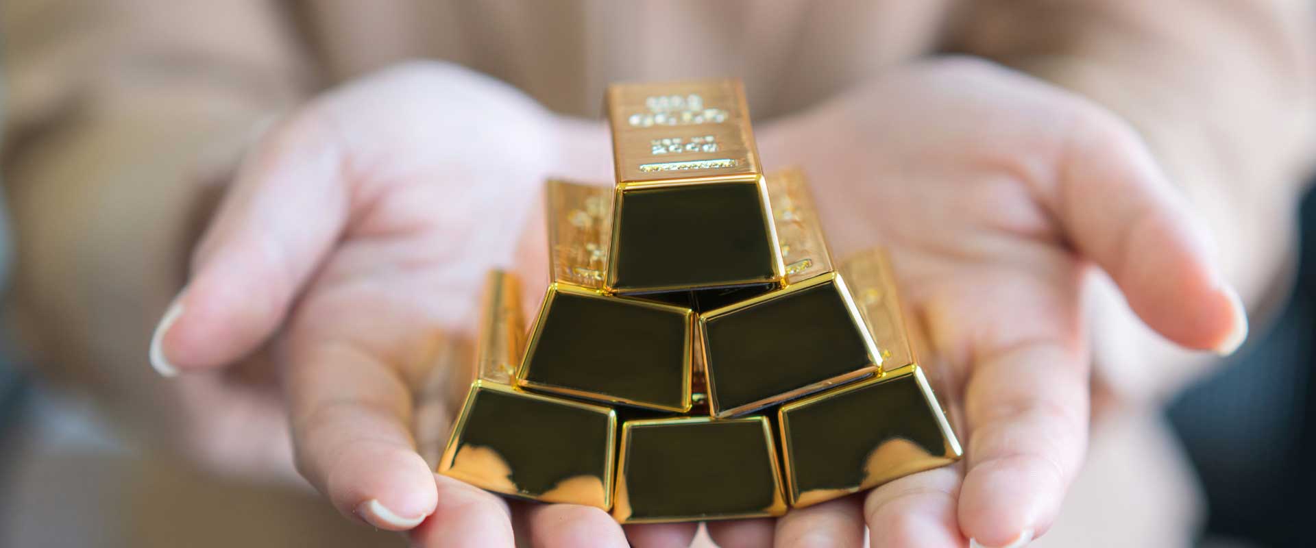 hands holding stack of gold bars