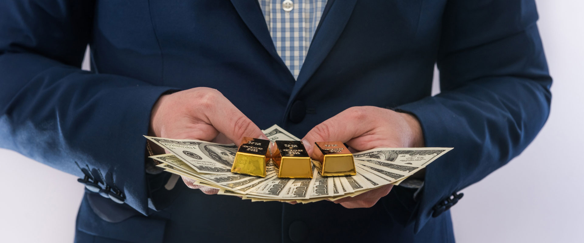 businessman holding hundred dollar bills with gold bars