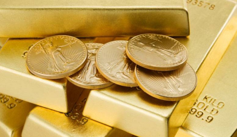 five gold coins on top of stacked gold bars
