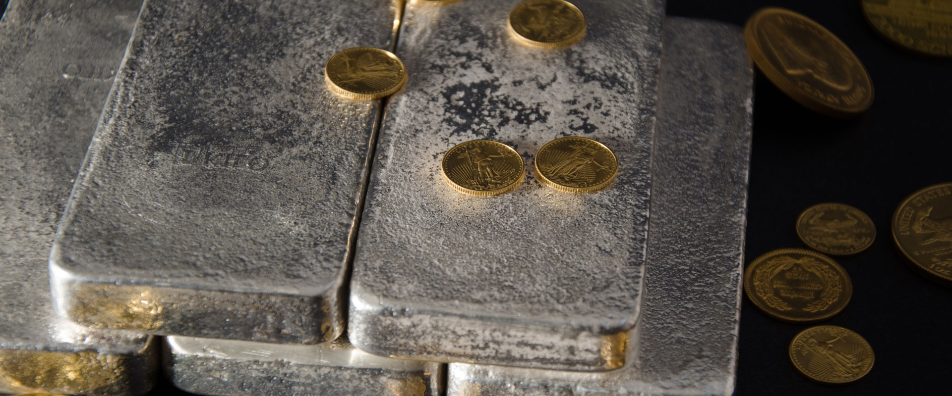 stack of silver bars with various gold coins