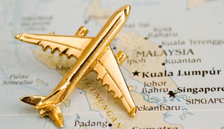 gold airplane model over singapore map