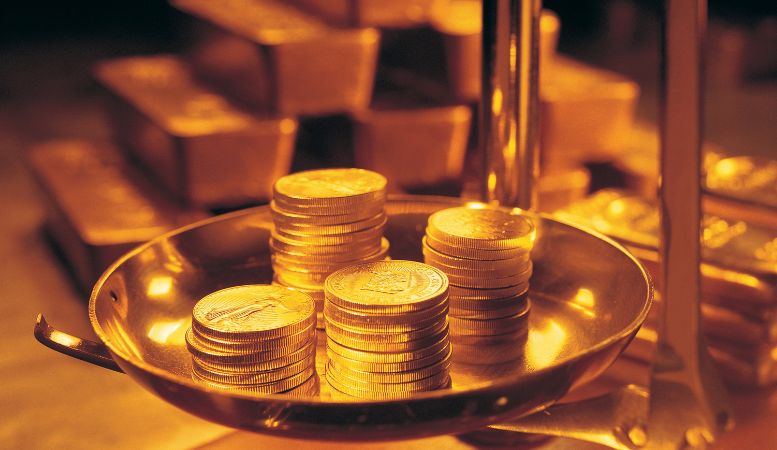 gold coins weighing with gold bars on background