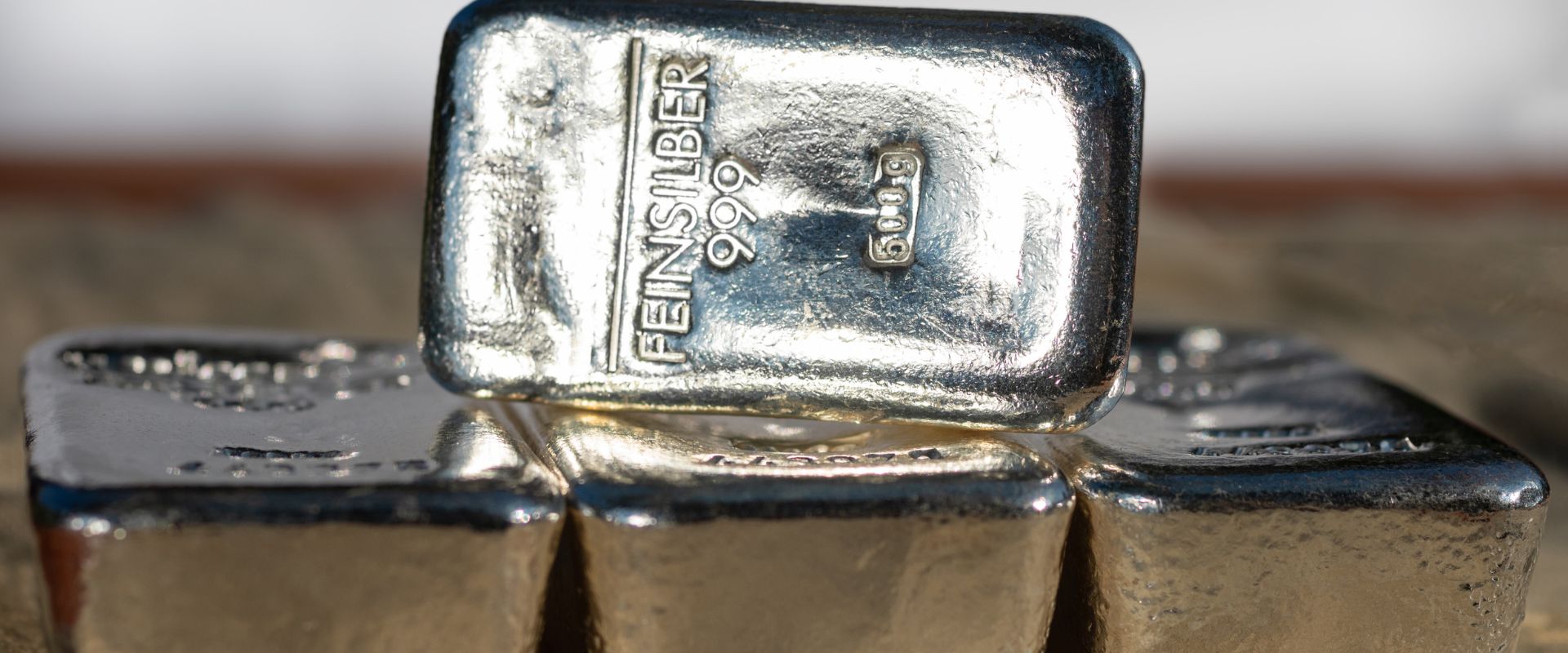 four cast silver bars against the blurred background