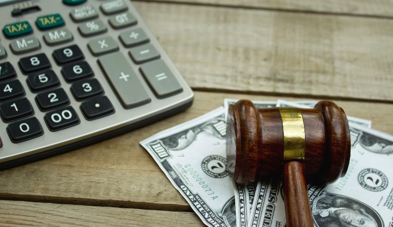 gavel calculator and us dollar banknotes on wooden table