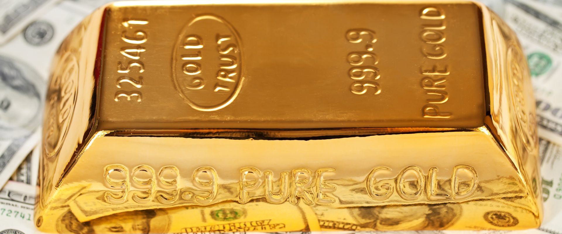 one kilogram pure gold bar on top on us dollar banknotes