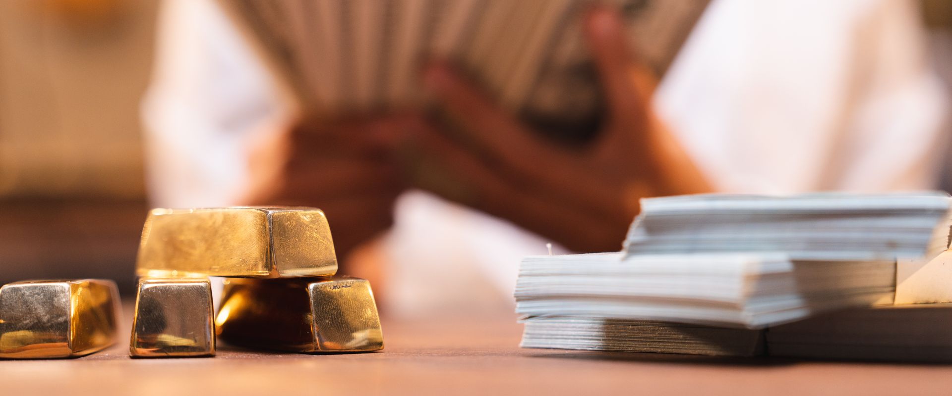 stack of shiny gold bar and dollar cash on blurred background