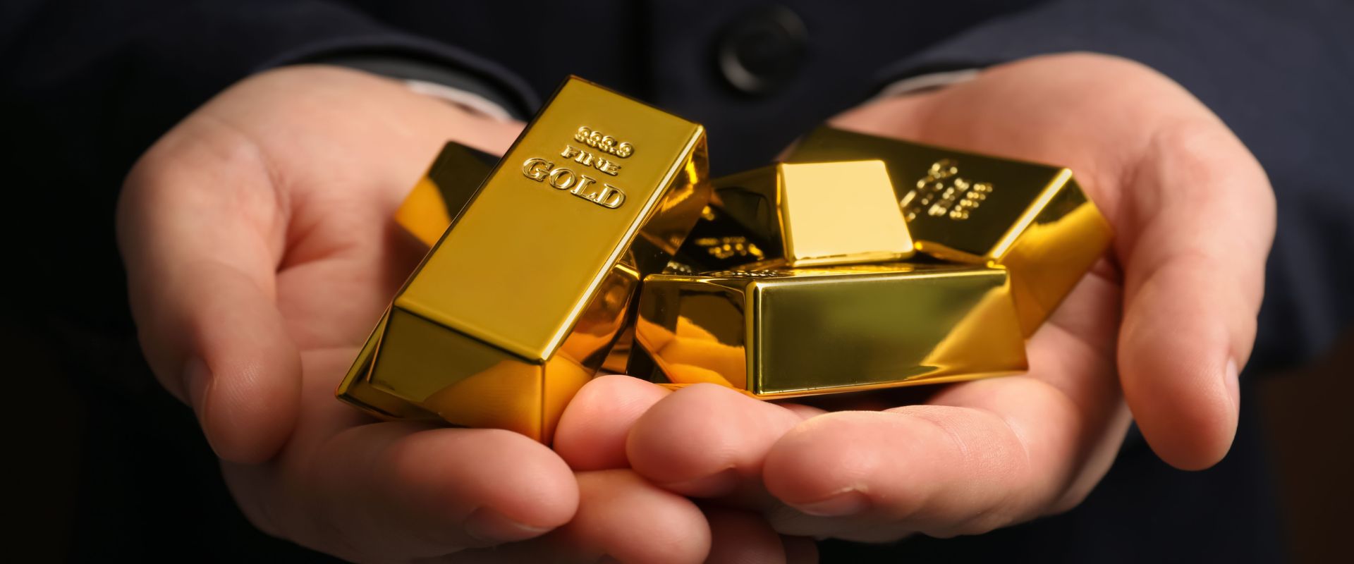 man holding many shiny gold bars