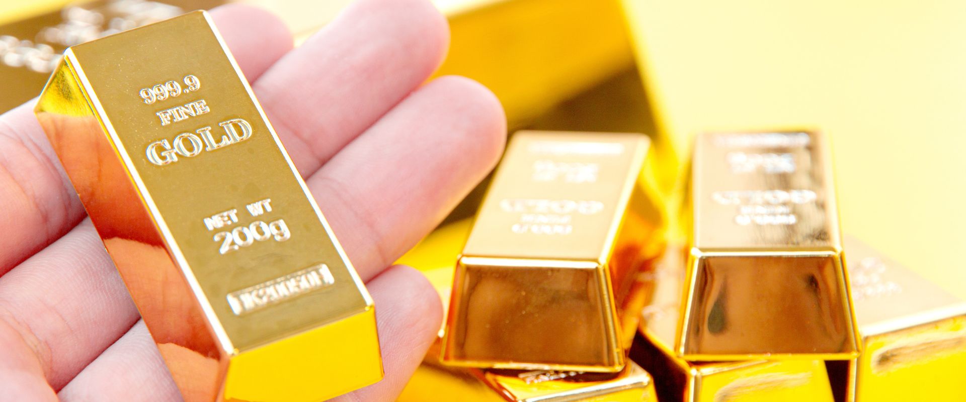 investor hand holding two hundred grams gold bar