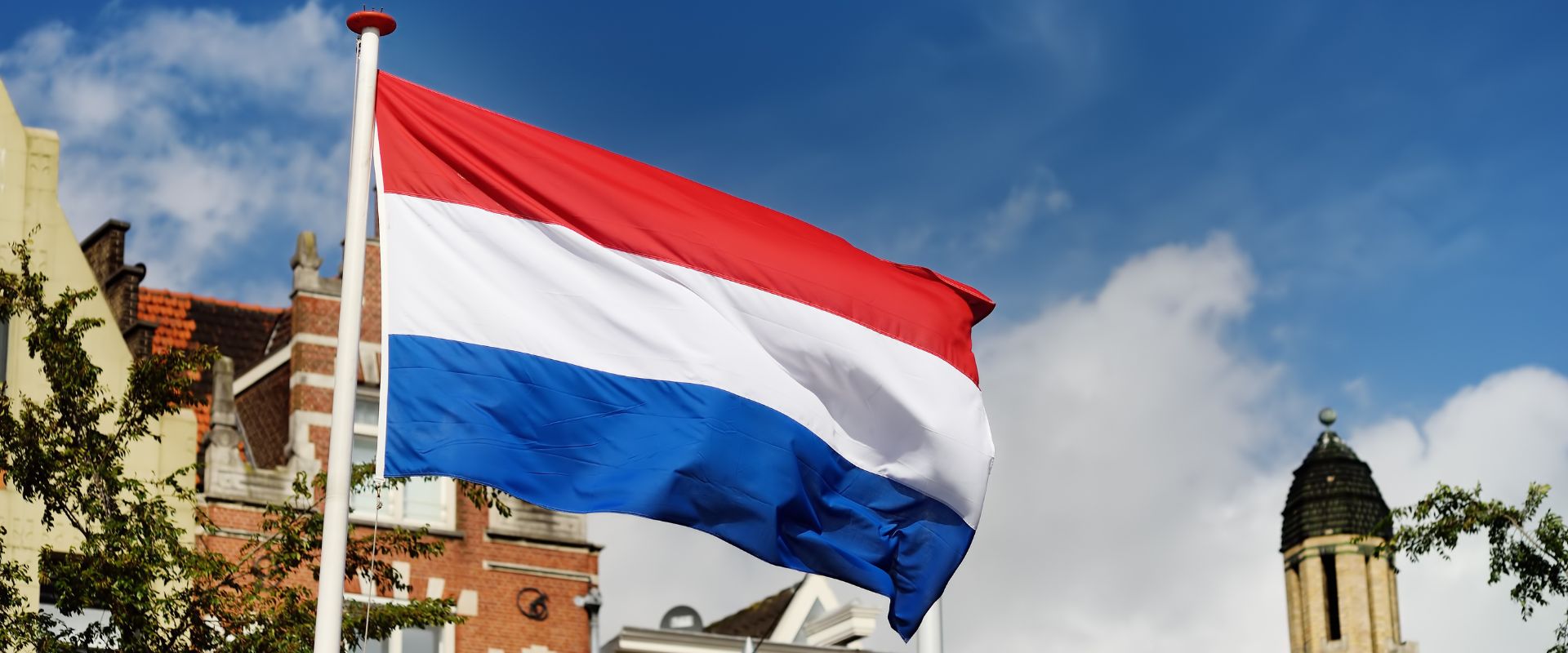 waving Dutch flag on building and sky background