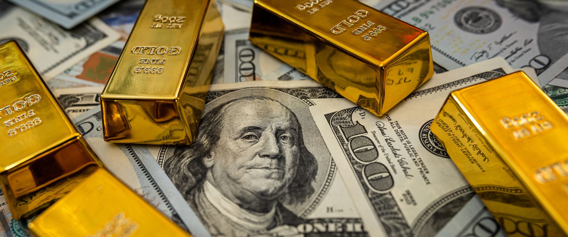 gold bullion on pile of US dollar bills as background